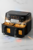 Black air fryer with open door showing interior on a light background